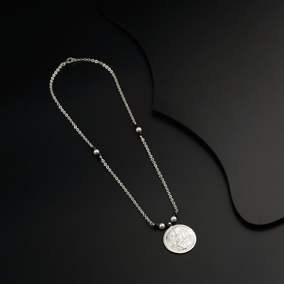 a necklace with a coin on a black background
