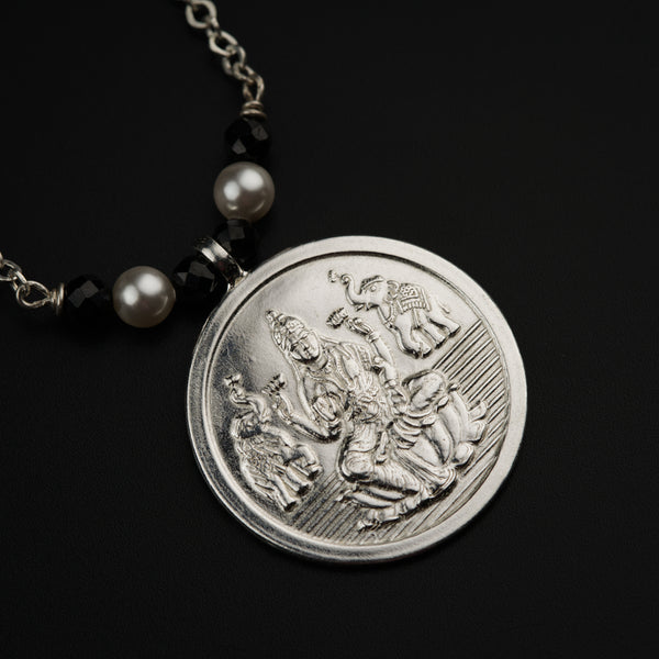 a necklace with a coin on a black background