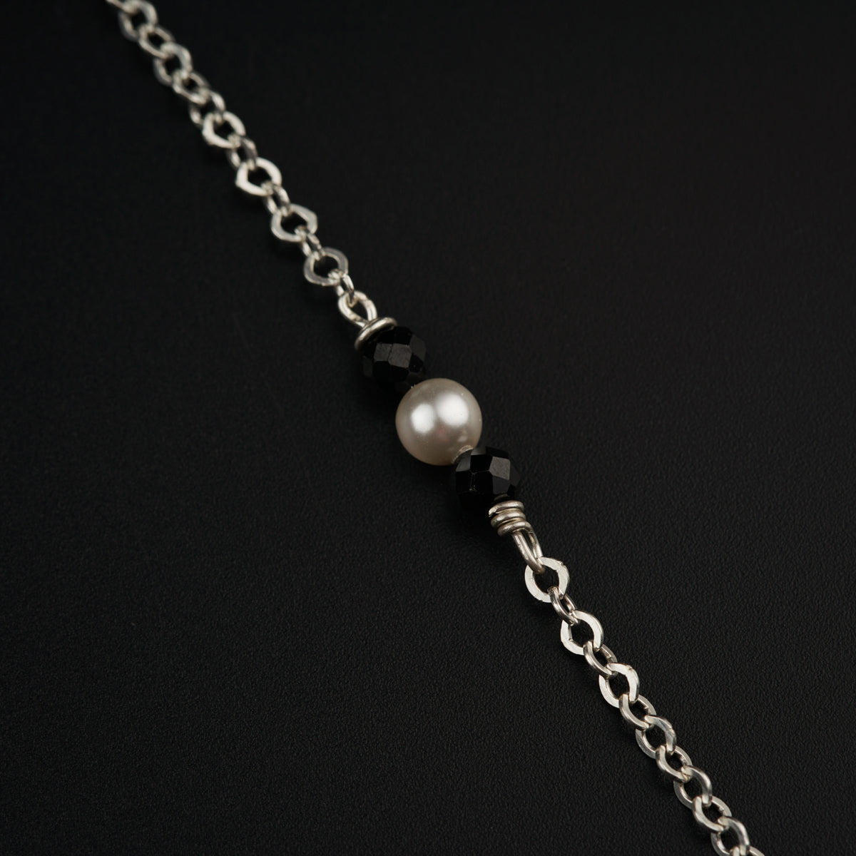 a silver chain with a white pearl on it
