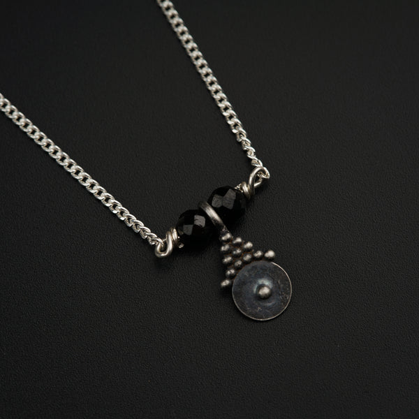 a black and silver necklace on a black surface
