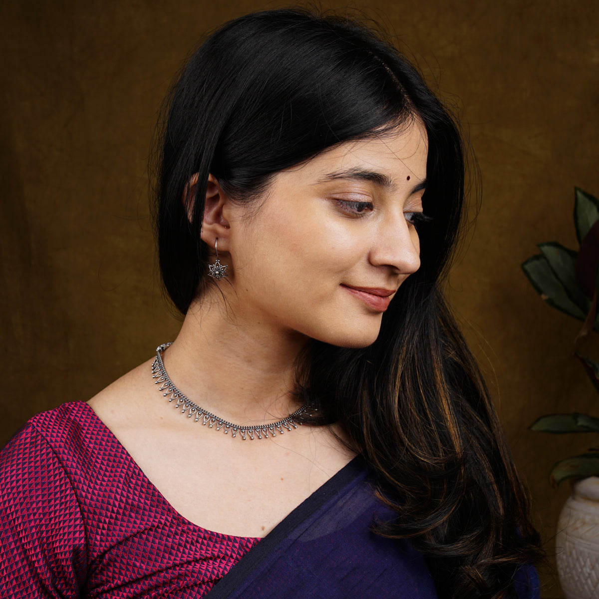 a woman wearing a necklace and a purple shirt