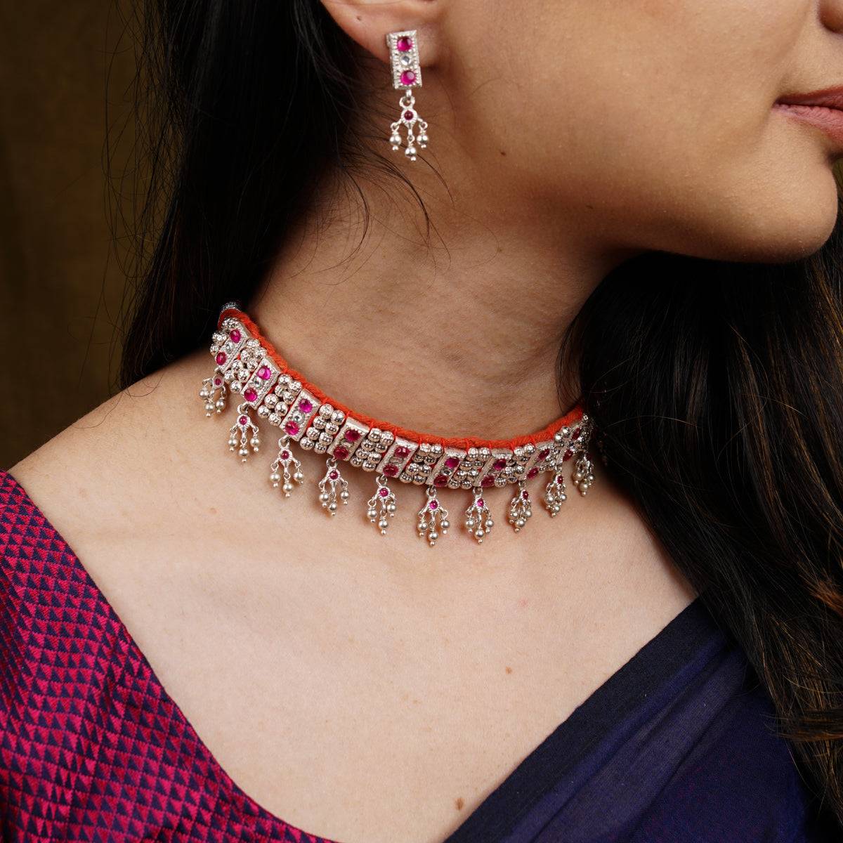 a close up of a woman wearing a necklace and earrings