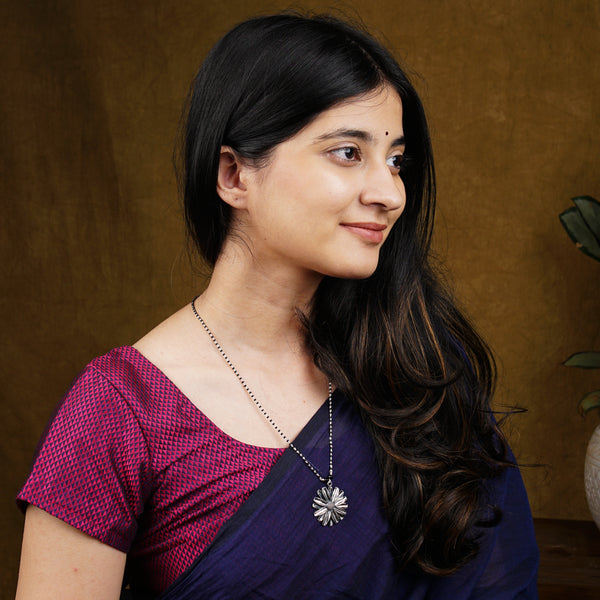 a woman wearing a purple blouse and a necklace