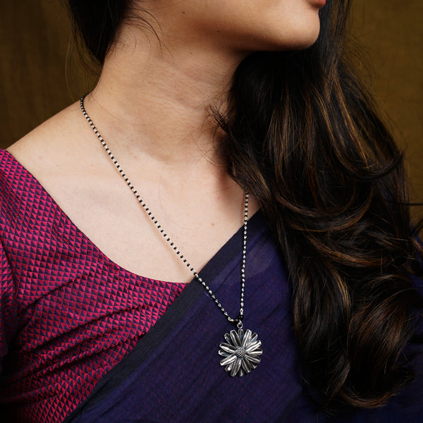 a woman wearing a necklace with a flower on it