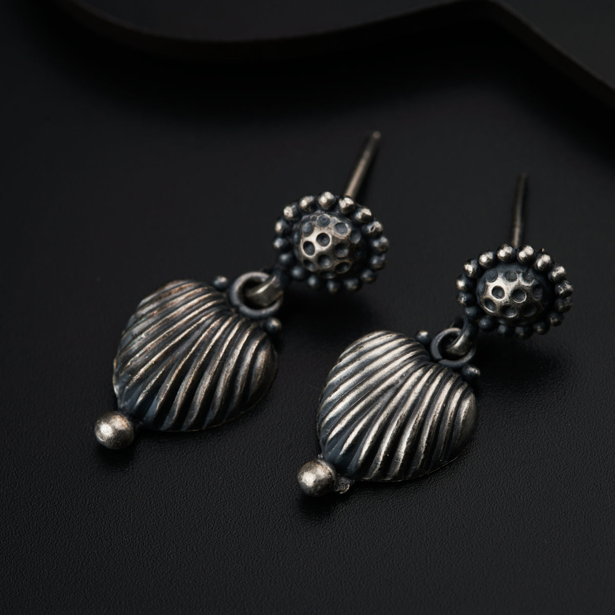 a pair of seashell earrings on a black surface