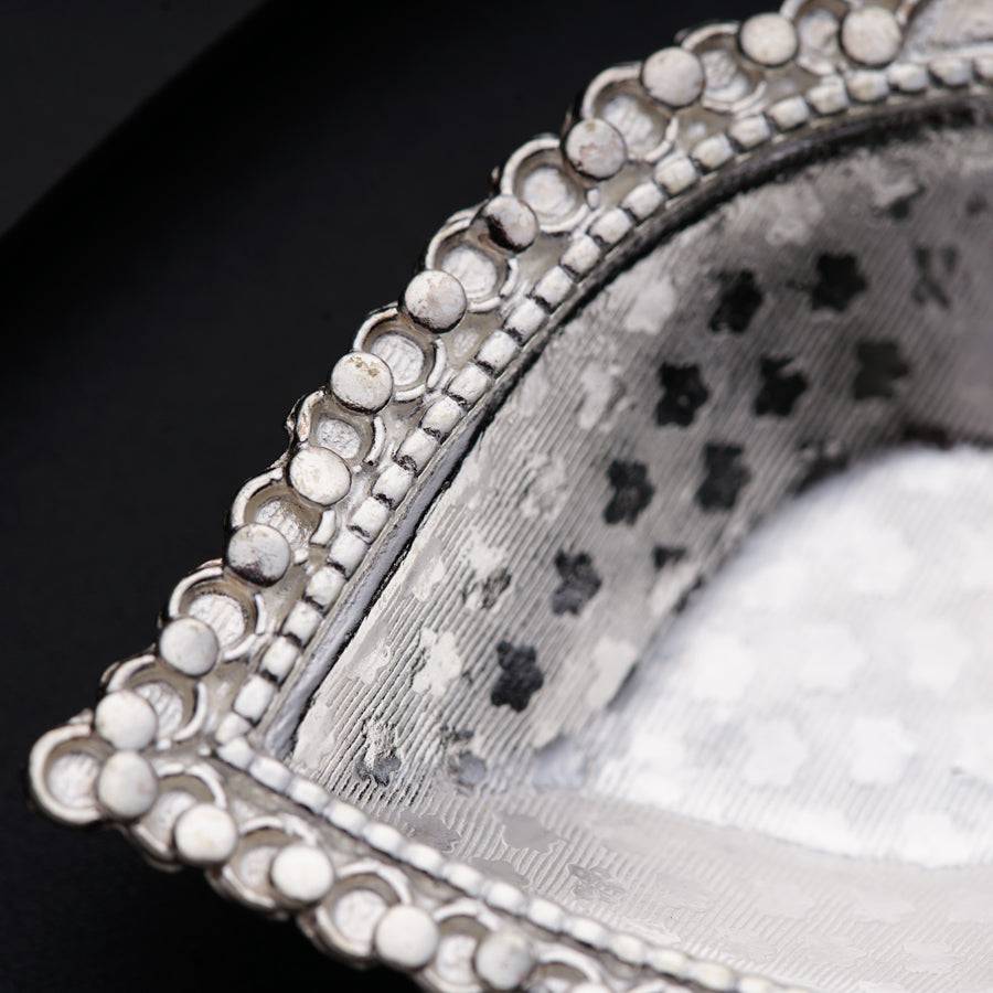 a close up of a silver purse on a black surface