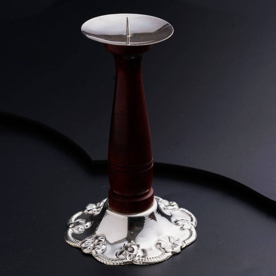 a silver and wood candle holder on a black surface