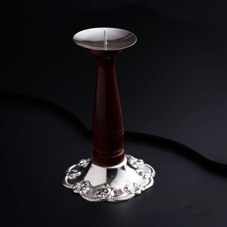 a silver and red candle holder on a black surface