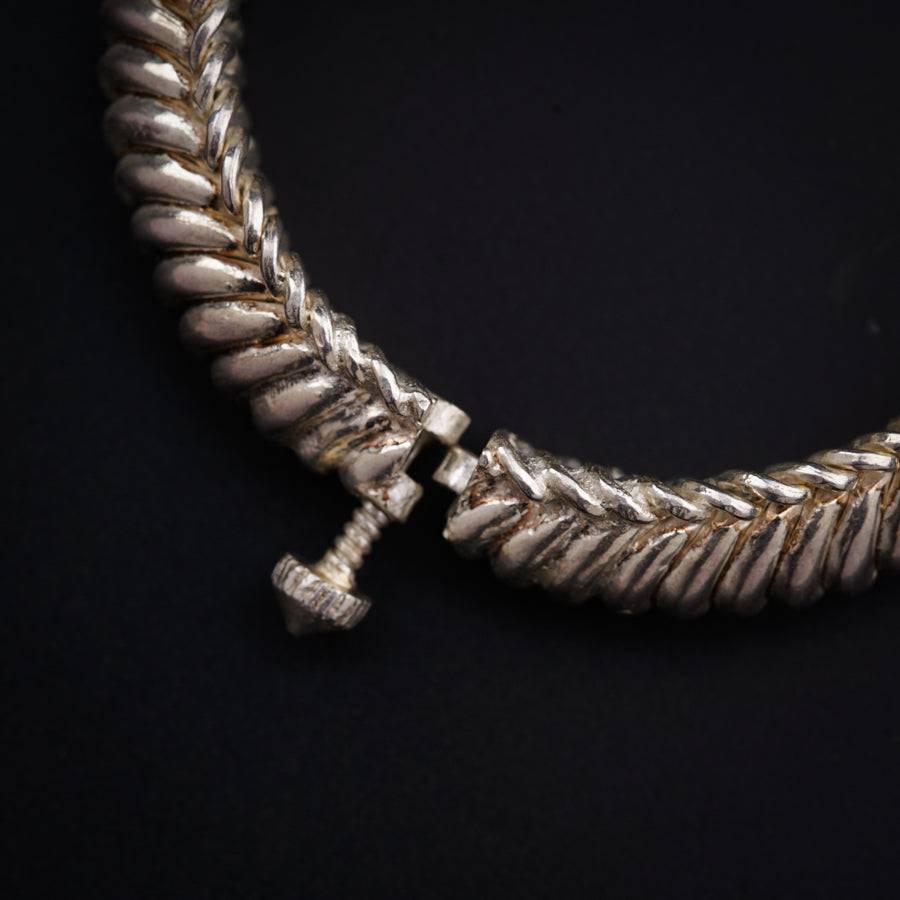 a close up of a silver necklace on a black background