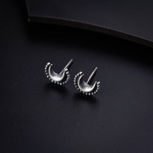 a pair of silver earrings sitting on top of a black surface
