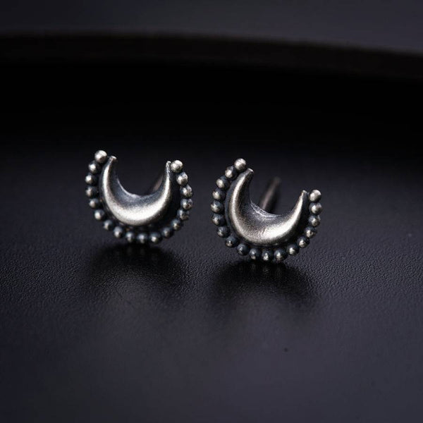a pair of silver earrings on a black surface