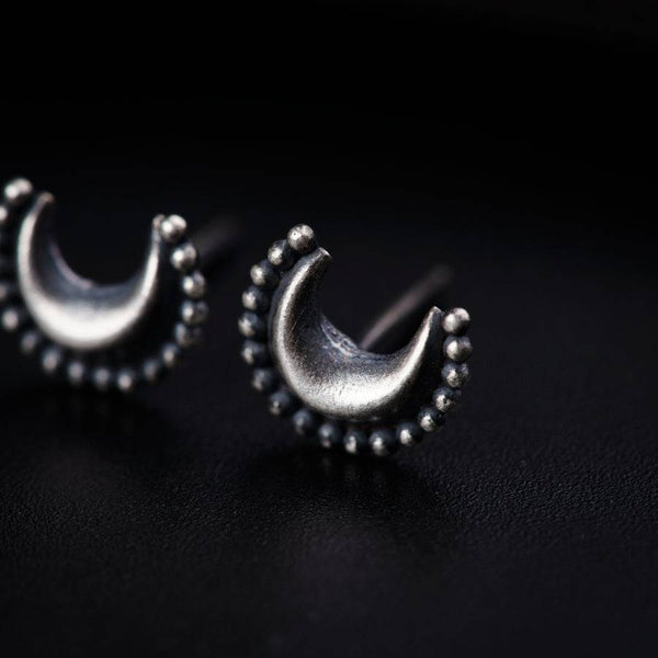 a pair of silver earrings sitting on top of a black surface