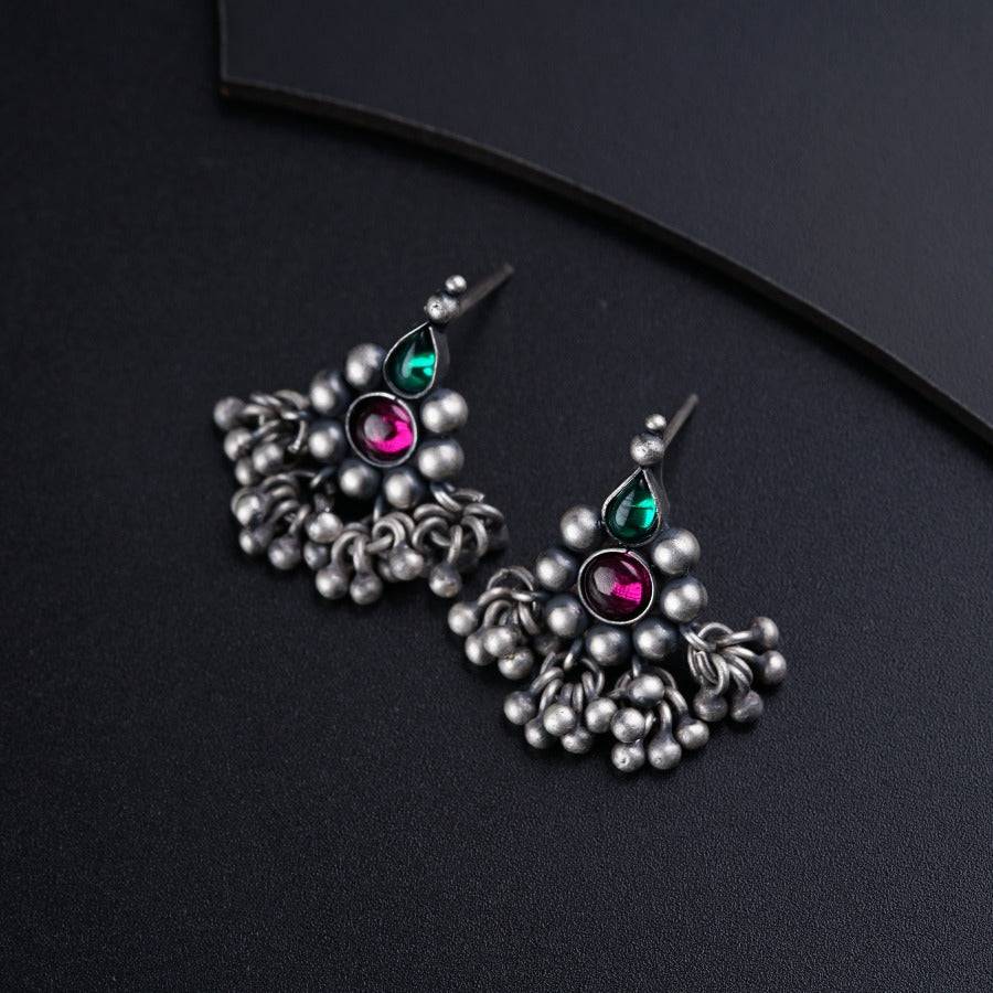 a pair of earrings with beads on a black surface