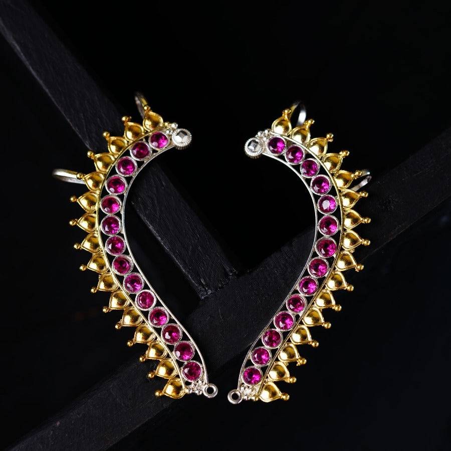 a pair of pink and gold earrings on a black background