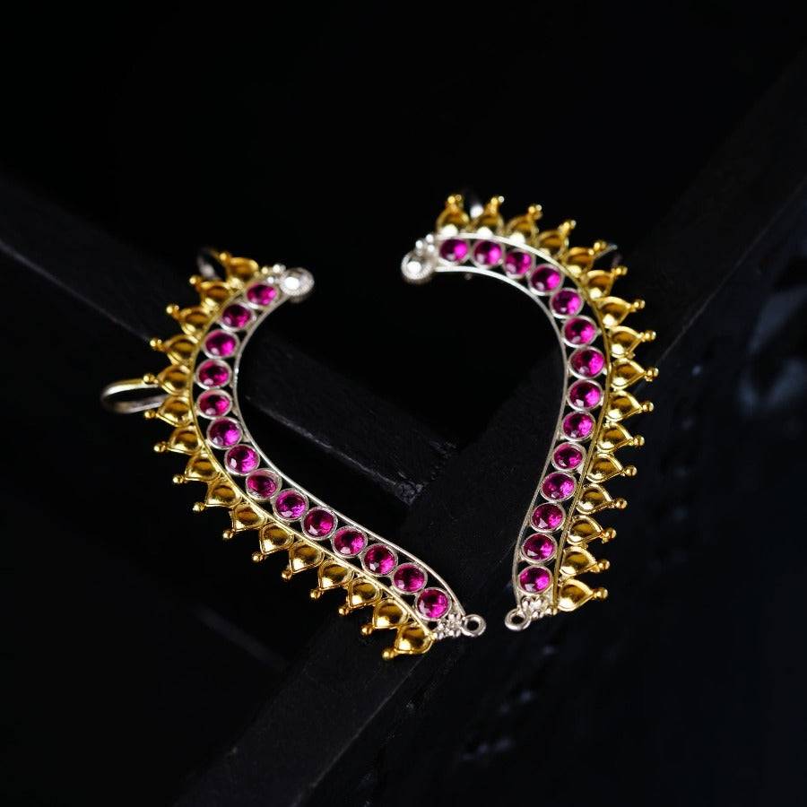 a pair of pink and gold earrings on a black surface