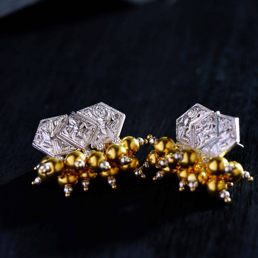 a pair of gold and silver earrings on a black surface