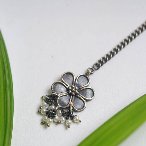 a necklace with a flower and pearls hanging from it
