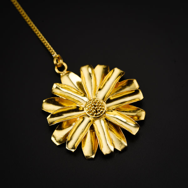 a gold necklace with a flower on a black background