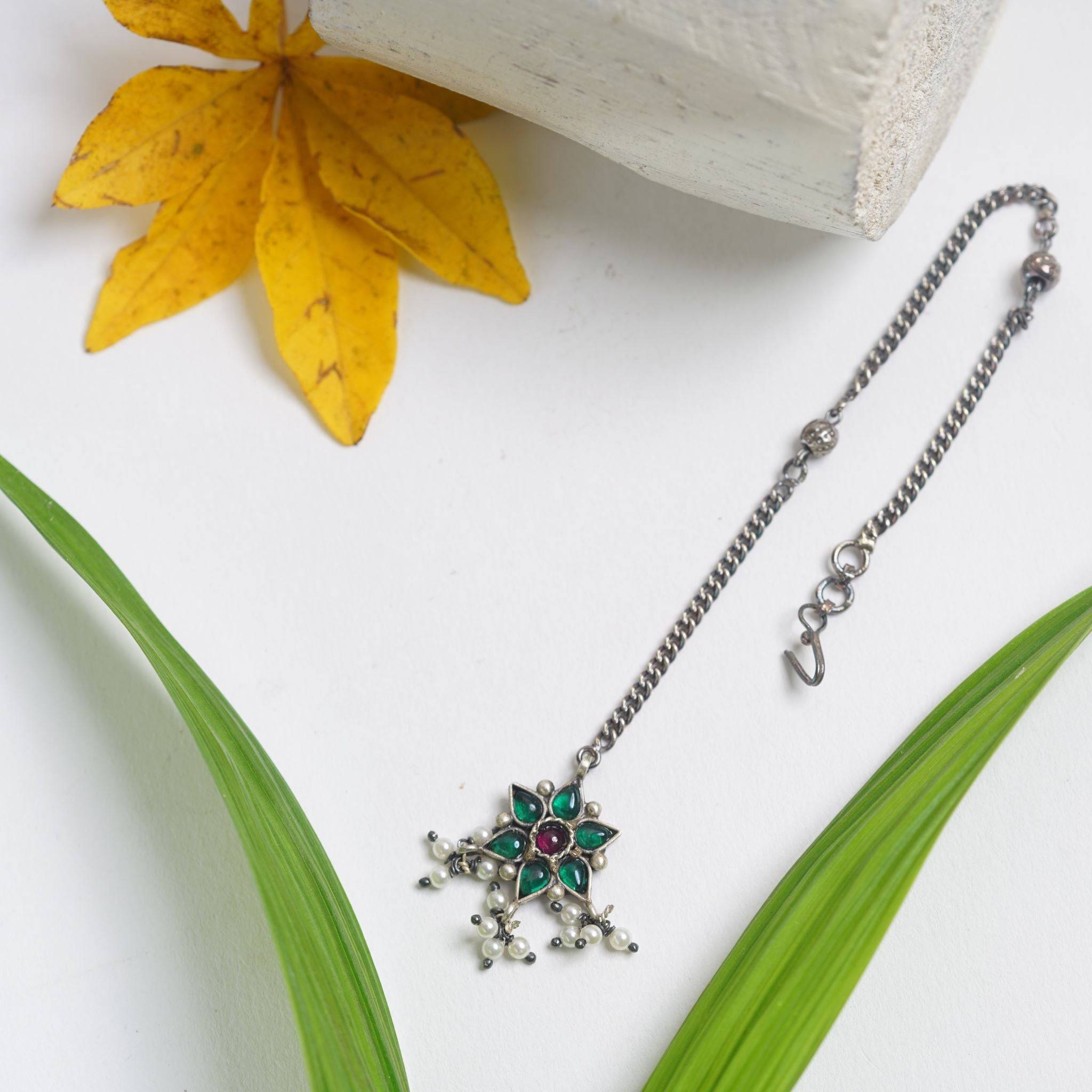 a necklace with a cross on it sitting next to a flower