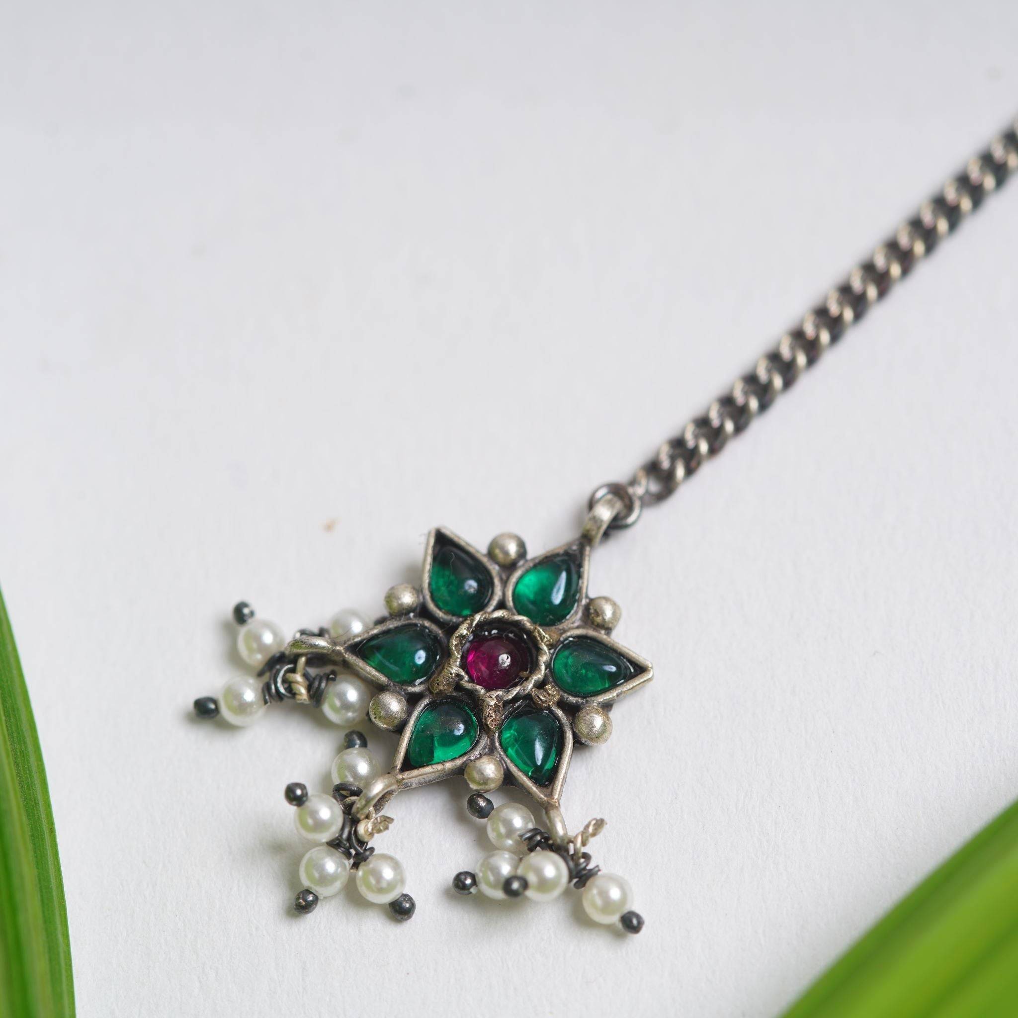 a green and white necklace on a white surface