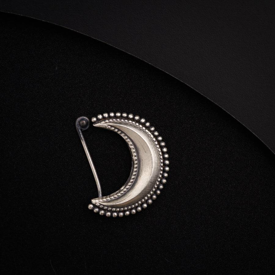 a silver brooch with beaded details on a black background