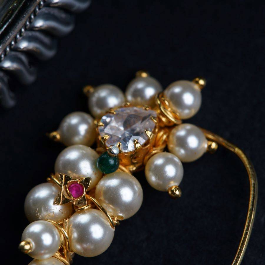 a close up of a brooch with pearls