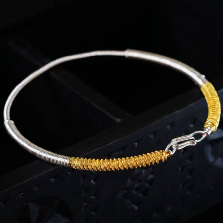 a yellow and silver bracelet on a black surface