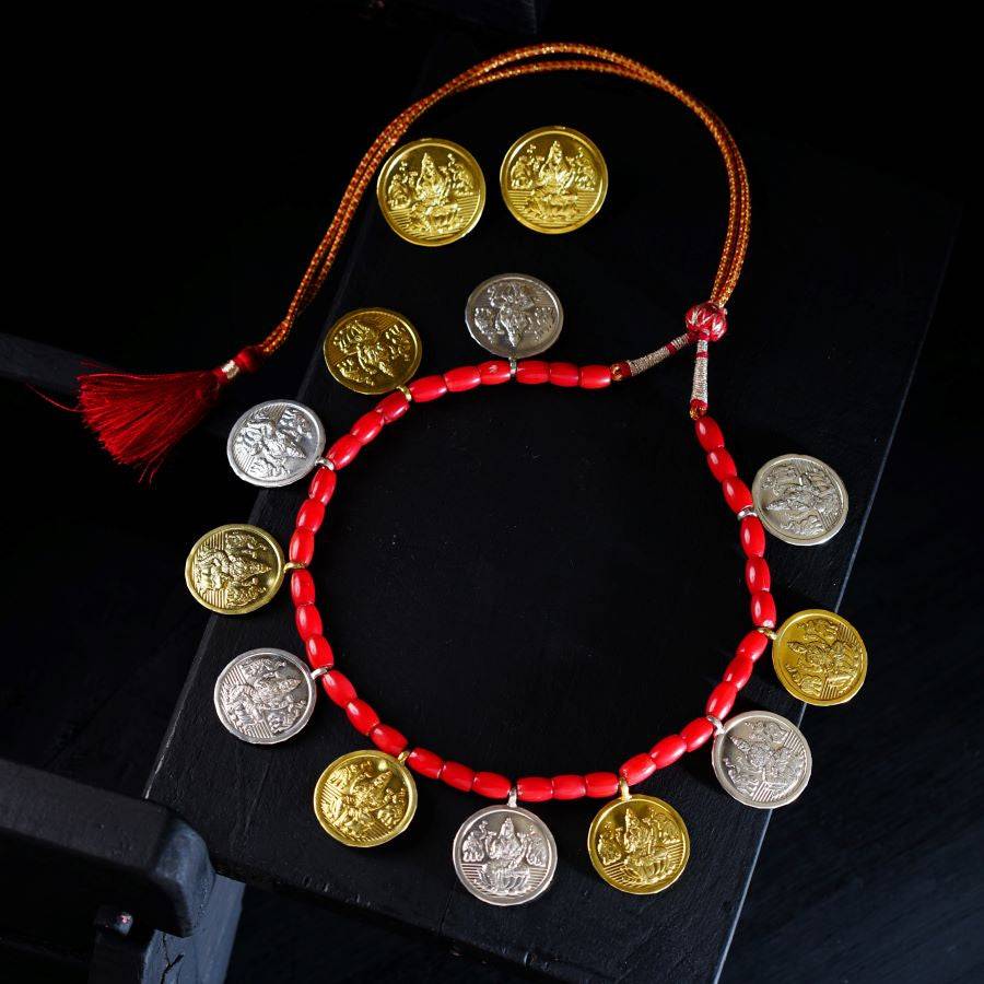 a red string bracelet with gold coins and a tassel
