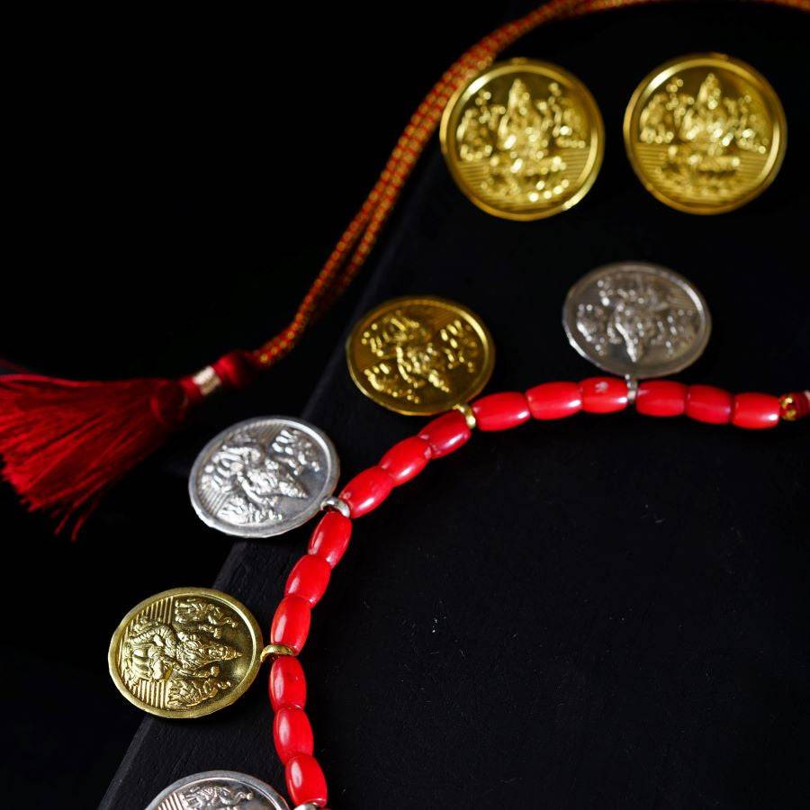 a red beaded necklace with gold coins and a tassel
