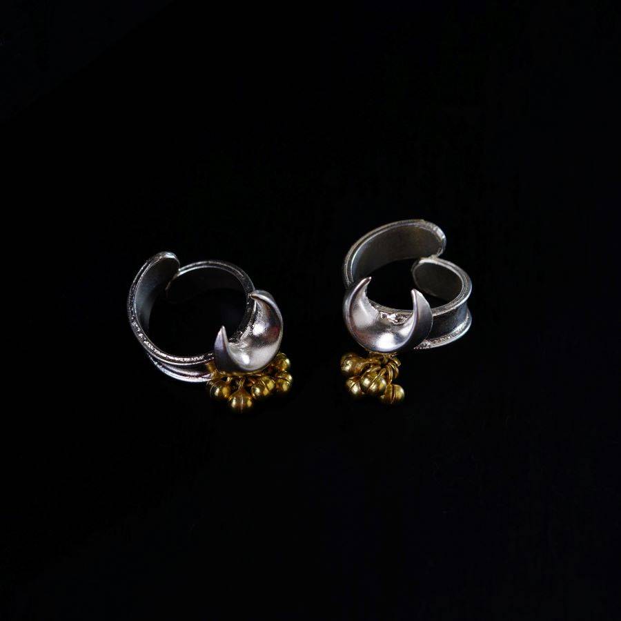 a pair of silver and gold earrings on a black background