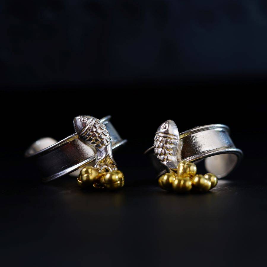 a pair of silver and gold earrings on a black surface
