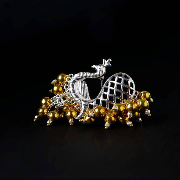 a silver and gold brooch sitting on top of a black surface