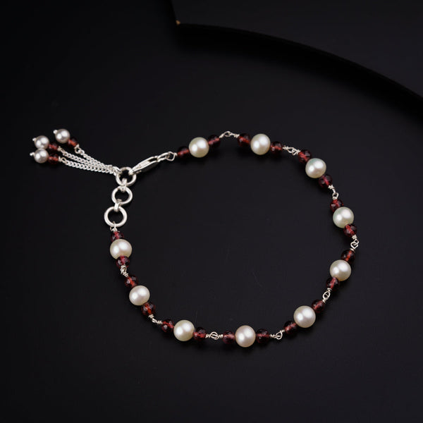 a red and white beaded bracelet on a black surface