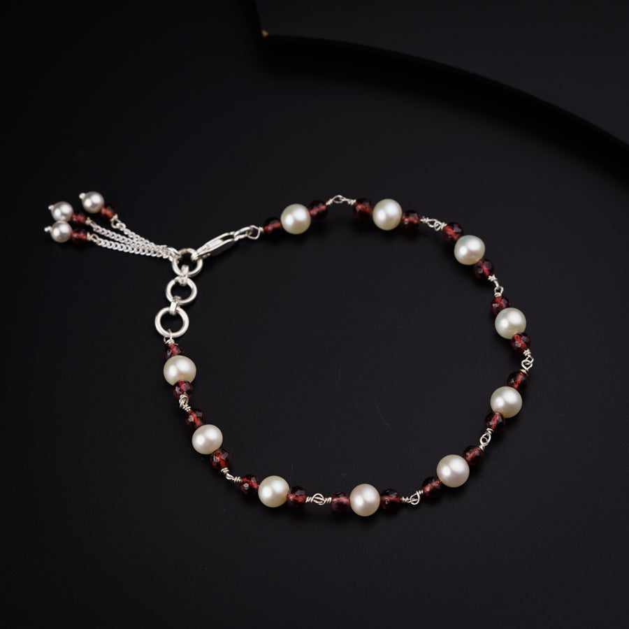 a red and white beaded bracelet on a black surface