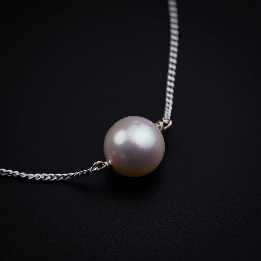 a white pearl on a chain on a black background