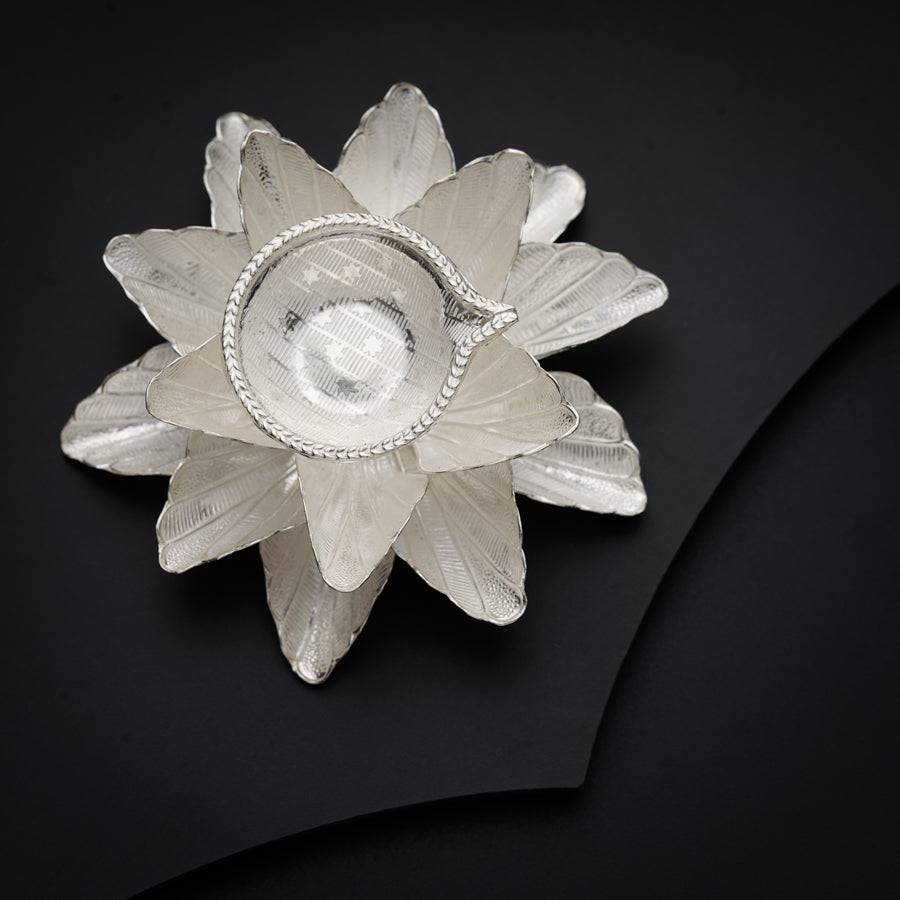 a glass flower brooch sitting on top of a black surface