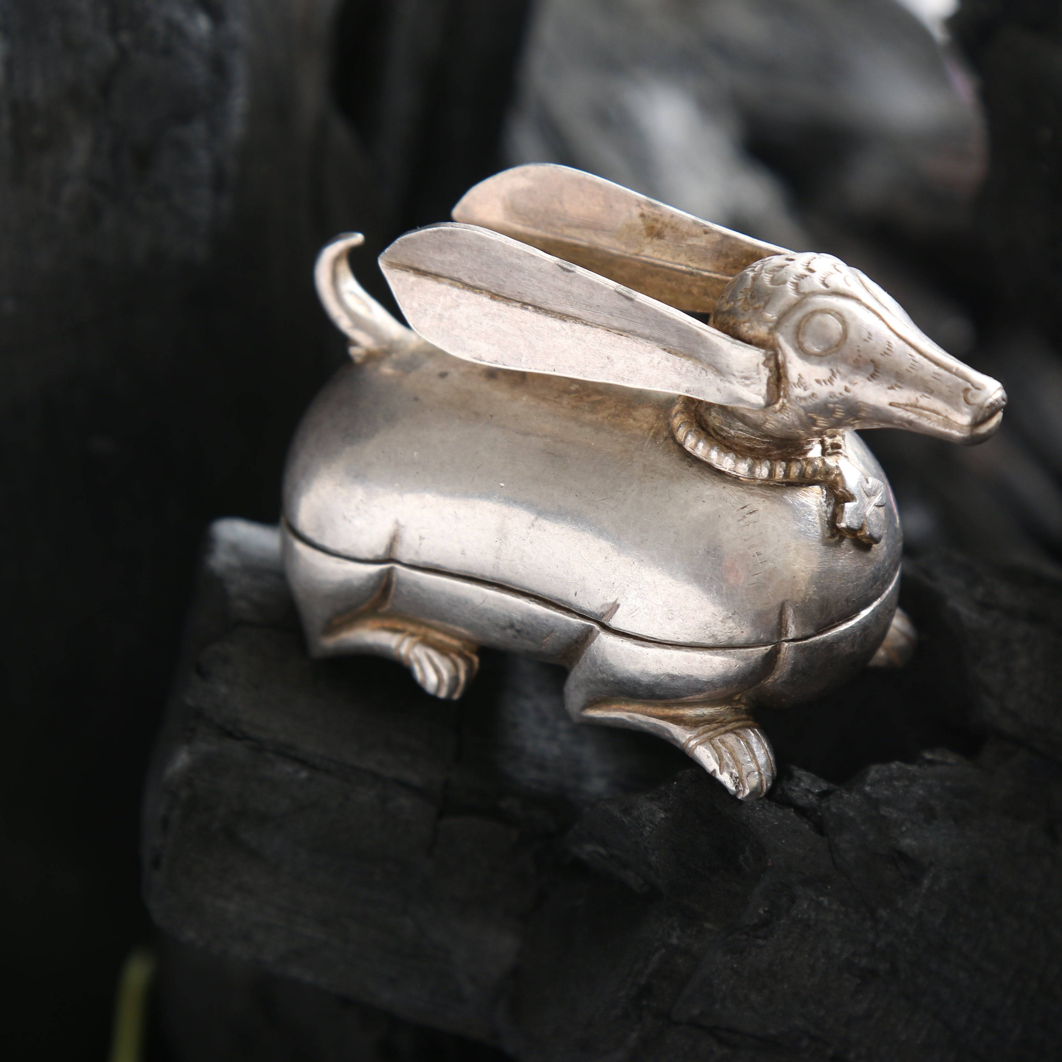 a silver rabbit figurine sitting on top of a rock