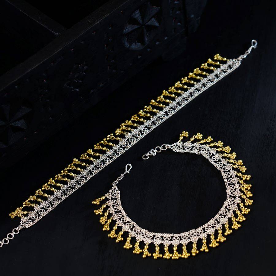 a gold and silver necklace and bracelet on a black surface