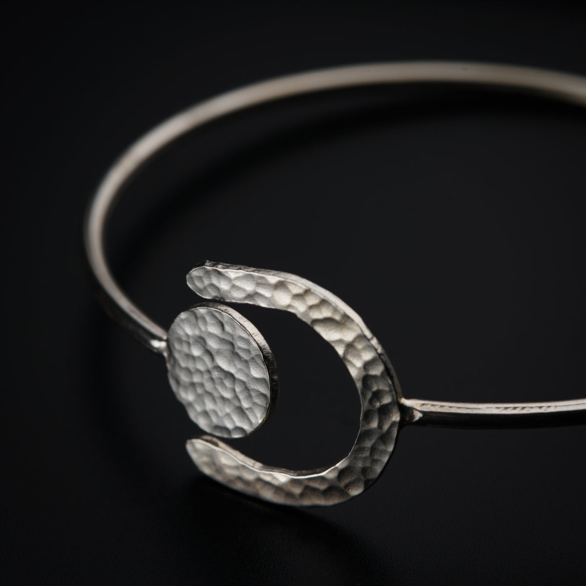 a close up of a silver bracelet on a black background