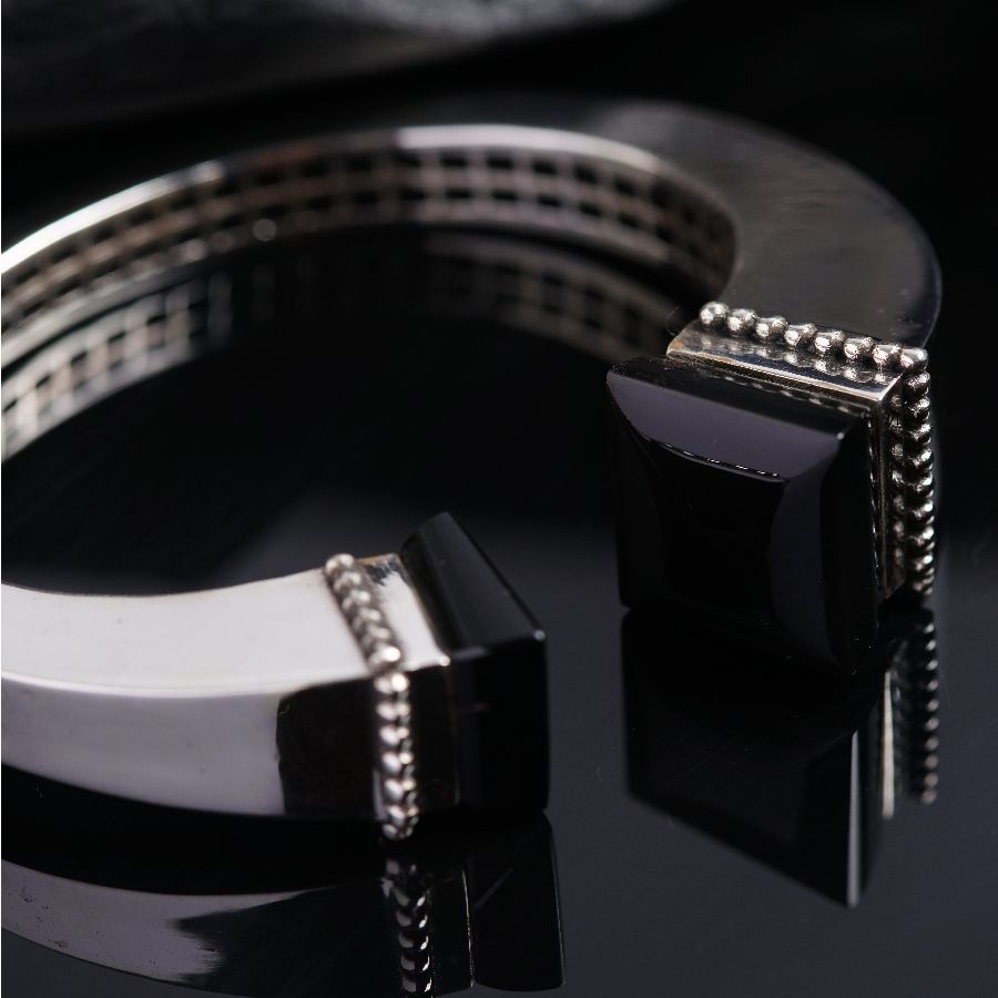a pair of black and silver bracelets on a black surface