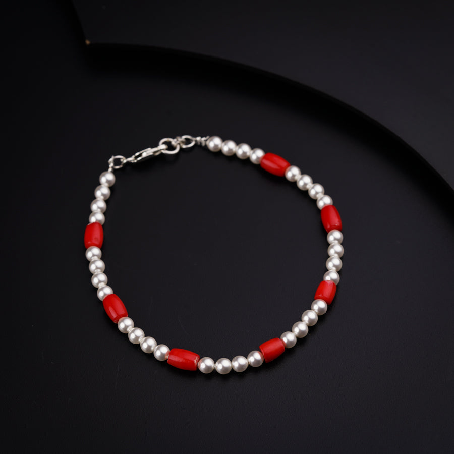 a red and silver beaded bracelet on a black surface