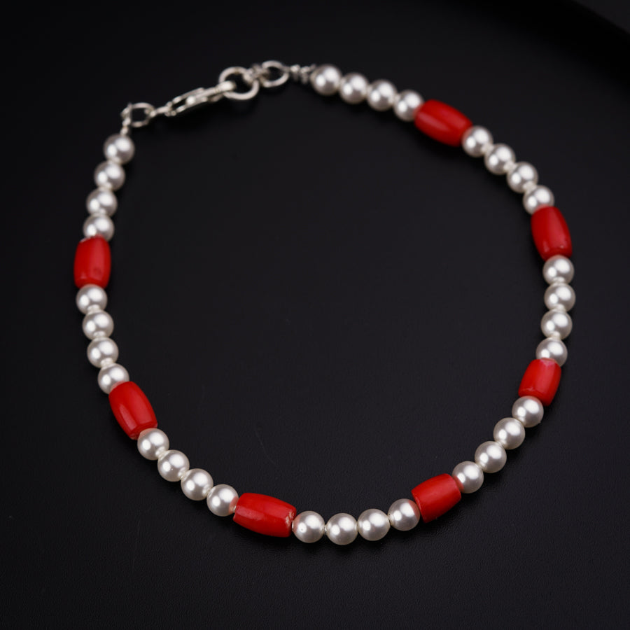 a red and silver beaded necklace on a black surface