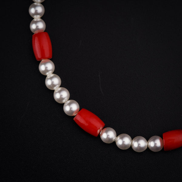a red and white necklace with pearls on a black background