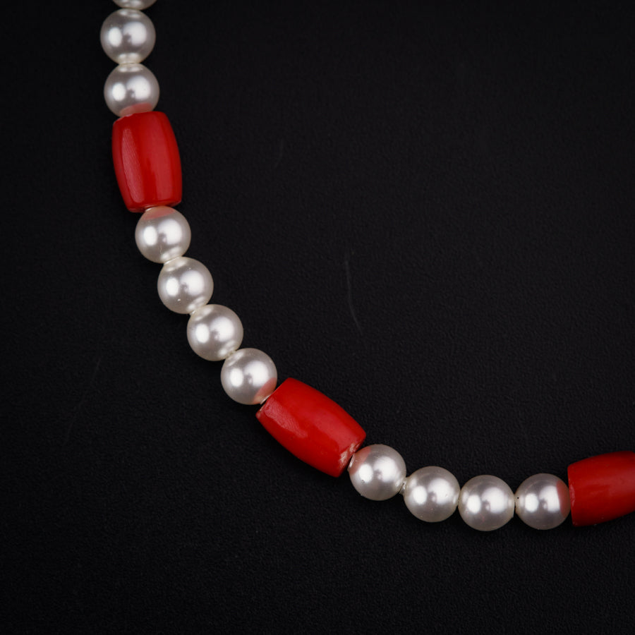 a red and white necklace with pearls on a black background