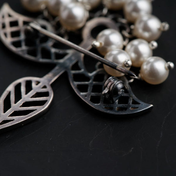 a close up of a brooch with pearls