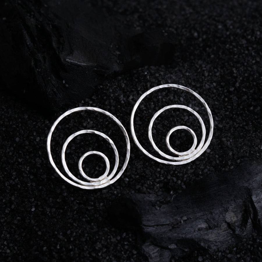 a pair of silver spiral earrings on a black background