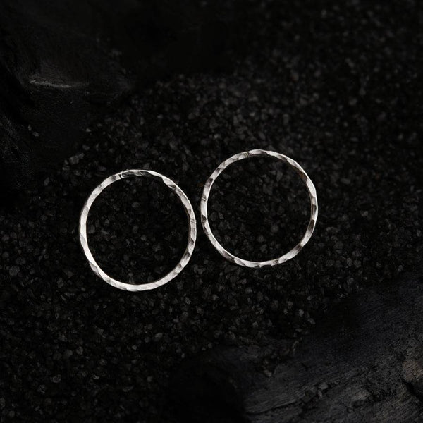 a pair of silver hoop earrings on a black background