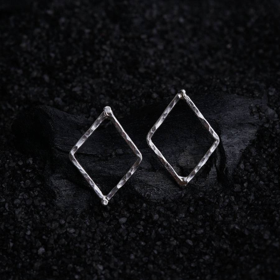 a pair of silver square earrings on a black background