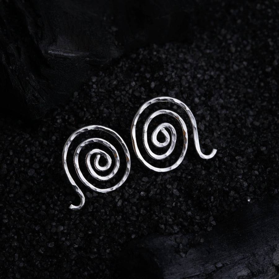 a pair of silver spiral earrings on a black background