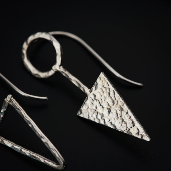 a pair of silver earrings on a black surface